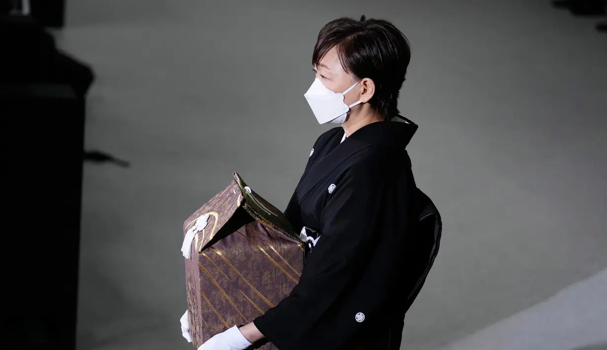 <p>Akie Abe, istri mantan Perdana Menteri Shinzo Abe, membawa guci berisi abu suaminya saat pemakaman kenegaraan di Nippon Budokan, Tokyo, Jepang, Selasa (27/9/2022). Proses pembawaan abu diiringi musik dentuman penghormatan. (Franck Robichon/Pool Photo via AP)</p>