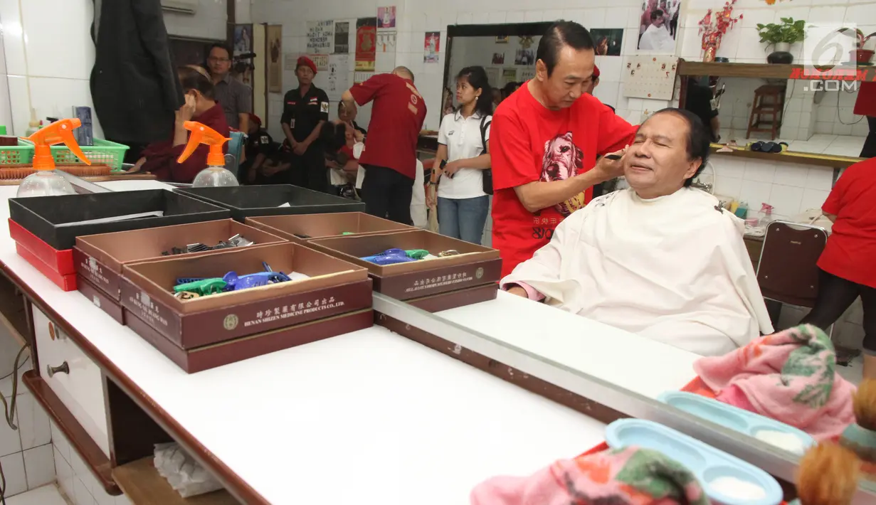 Mantan Menko Bidang Kemaritiman Rizal Ramli saat mencukur rambut di kawasan Glodok, Jakarta Barat, Kamis (15/2). Rizal menembus lorong yang tergenang air dan berdialog dengan pedagang. (Liputan6.com/Pool/Yasin)