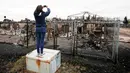 Seorang wanita mengambil foto sisa-sisa kebakaran hutan yang terjadi beberapa hari lalu di kAbasand, Fort McMurray, Alberta, Kanada, (9/5). Kebakaran ini menghanguskan 7.500 hektare lahan. (REUTERS/Chris Wattie)