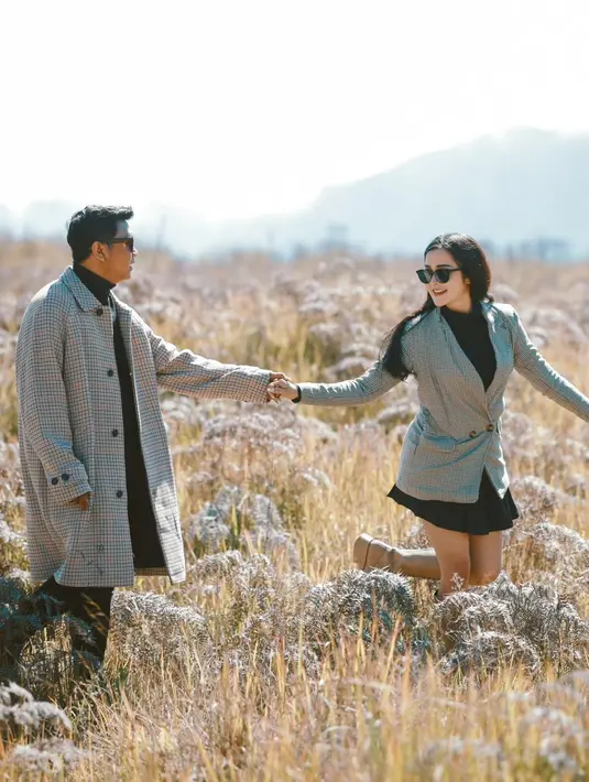 Kesan warm terpancar dalam konsep pemotretan ketiga Denny dan Bella di tengah hamparan rumput alang-alang. [Instagram/denny_caknan]