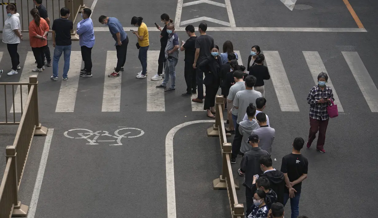 <p>Warga dan pekerja kantor yang mengenakan masker berbaris di jalan untuk pengujian virus corona massal di dekat kompleks perumahan dan perkantoran komersial di kawasan pusat bisnis, Beijing, Senin (25/4/2022). (AP Photo/Andy Wong)</p>