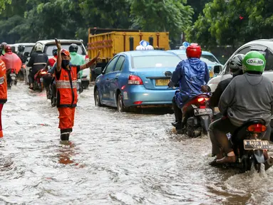 Petugas PPSU Srengseng Sawah melakukan pengaturan kendaraan yang melintas di jalan Lenteng agung, Jakarta, (12/2). Akibat Hujan deras,  jalan Lenteng Agung tepat di depan Universitas Pancasila  tergenang banjir hingga 50 cm. (Liputan6.com/Yoppy Renato)