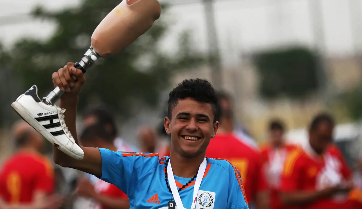 Seorang remaja Irak menunjukkan kaki palsunya saat bermain sepak bola di Arbil, Irak utara (7/5). Mereka semangat bermain sepak bola meski menggunakan kaki palsu. (AFP/Safin Hamed)