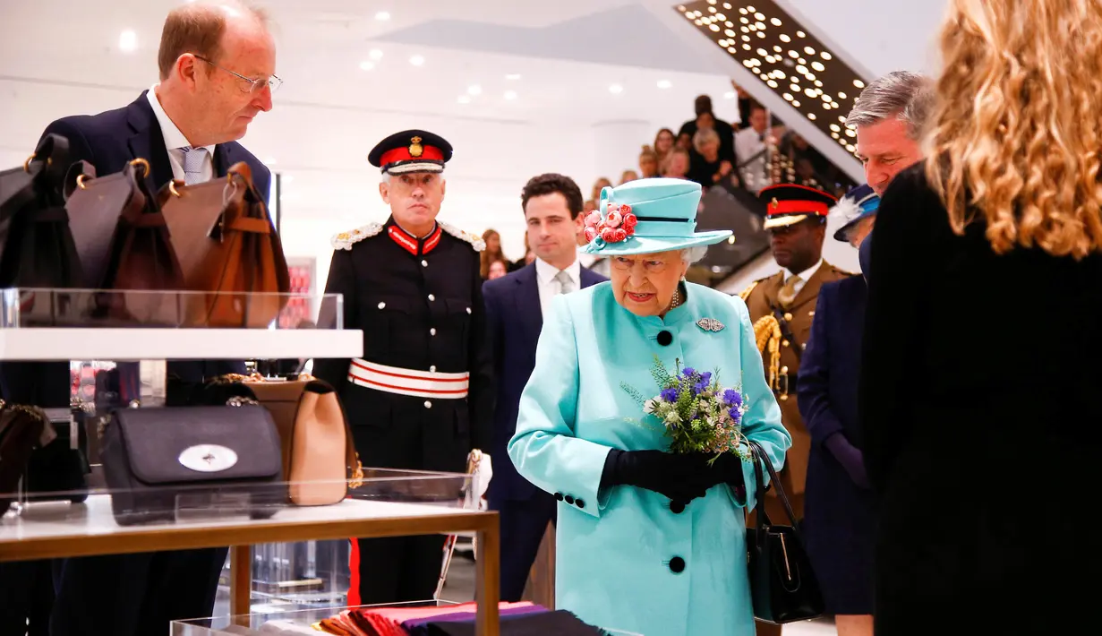 Ratu Elizabeth II melihat-lihat etalase tas di department store Fenwick saat mengunjungi pusat perbelanjaan Lexicon di Bracknell, London, Jumat (19/10). Ratu Elizabeth berjalan mengamati aksesoris sambil memegang buket bunga. (AP Photo Pool)