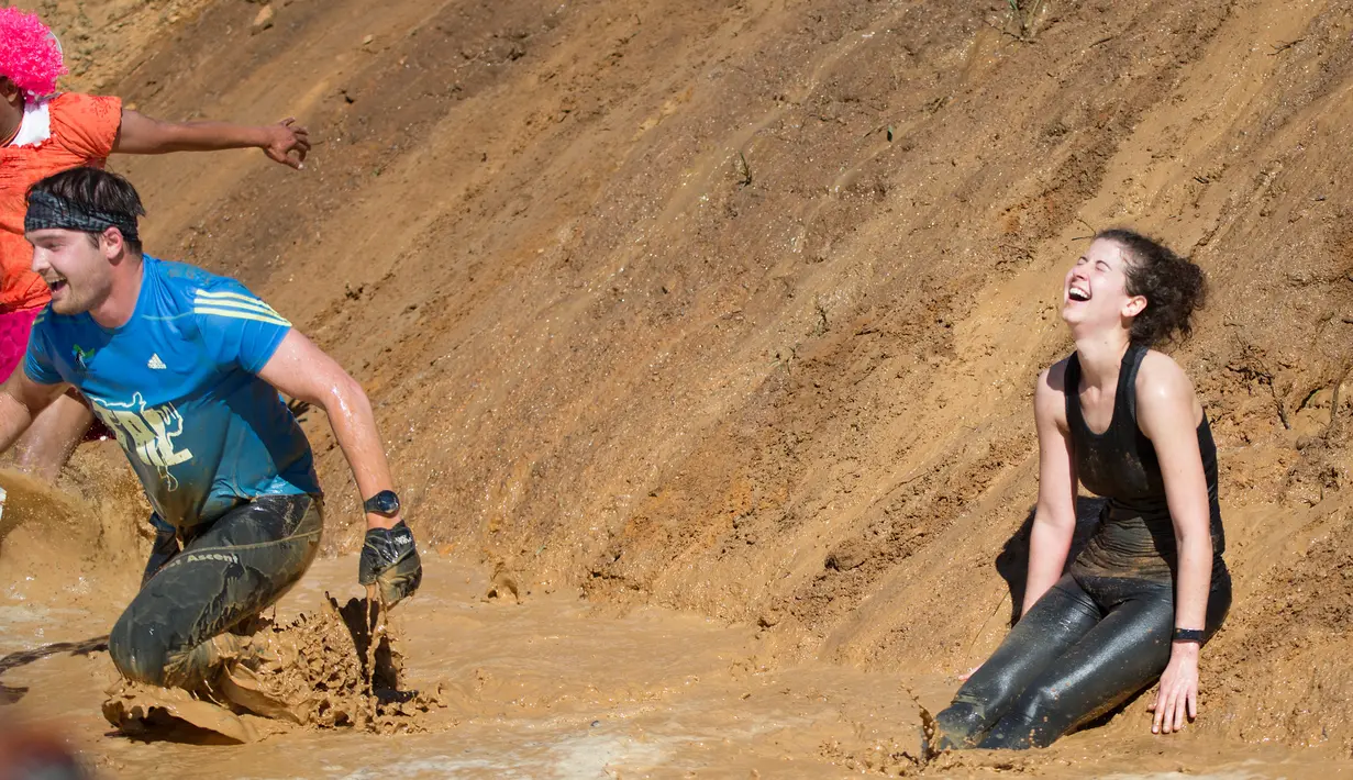 Peserta melintasi lubang lumpur saat ambil bagian dalam lomba lari Strongman Run di kota Paarl, Afrika Selatan, 13 Oktober 2018. Strongman Run adalah lomba lari halang rintang untuk menguji kecepatan dan daya tahan. (RODGER BOSCH/AFP)