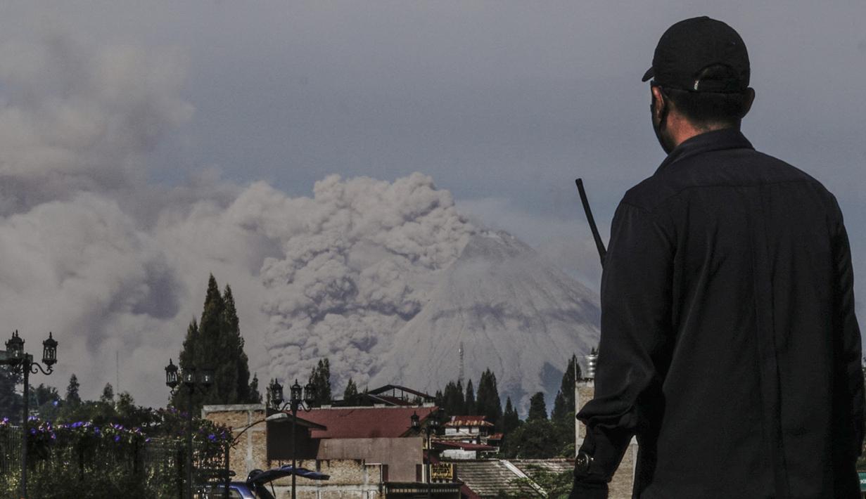 Seorang pria menyaksikan Gunung Sinabung memuntahkan abu saat erupsi terlihat dari Kabupaten Brastagi di Karo, Sumatera Utara (11/3/2021). Gunung berapi tersebut mengeluarkan longsoran awan gas membakar yang mengalir menuruni lerengnya saat terjadi letusan pada hari Kamis. (AFP/Sugeng Nuryono)