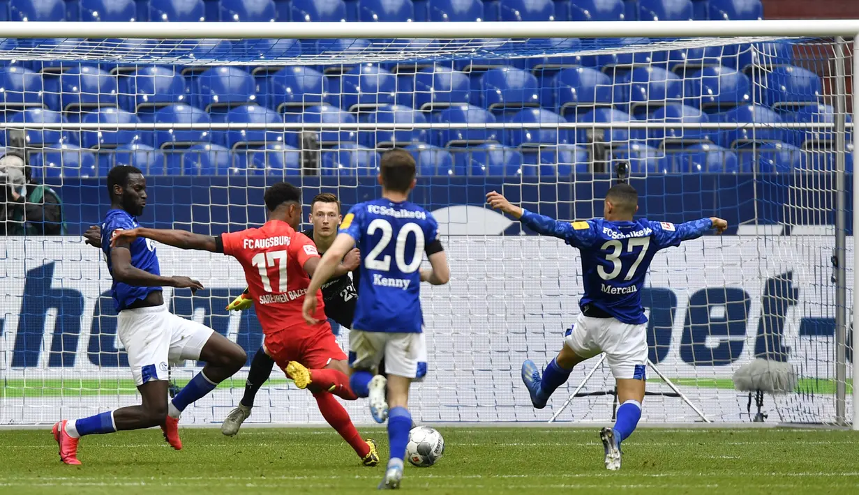 Pemain Augsburg, Noah Saranren Bazee, mencetak gol ke gawang Schalke 04 pada laga Bundesliga di Veltins-Arena, Minggu (24/5/2020). Augsburg menang dengan skor 3-0 atas Schalke 04. (AP/Martin Meissner)