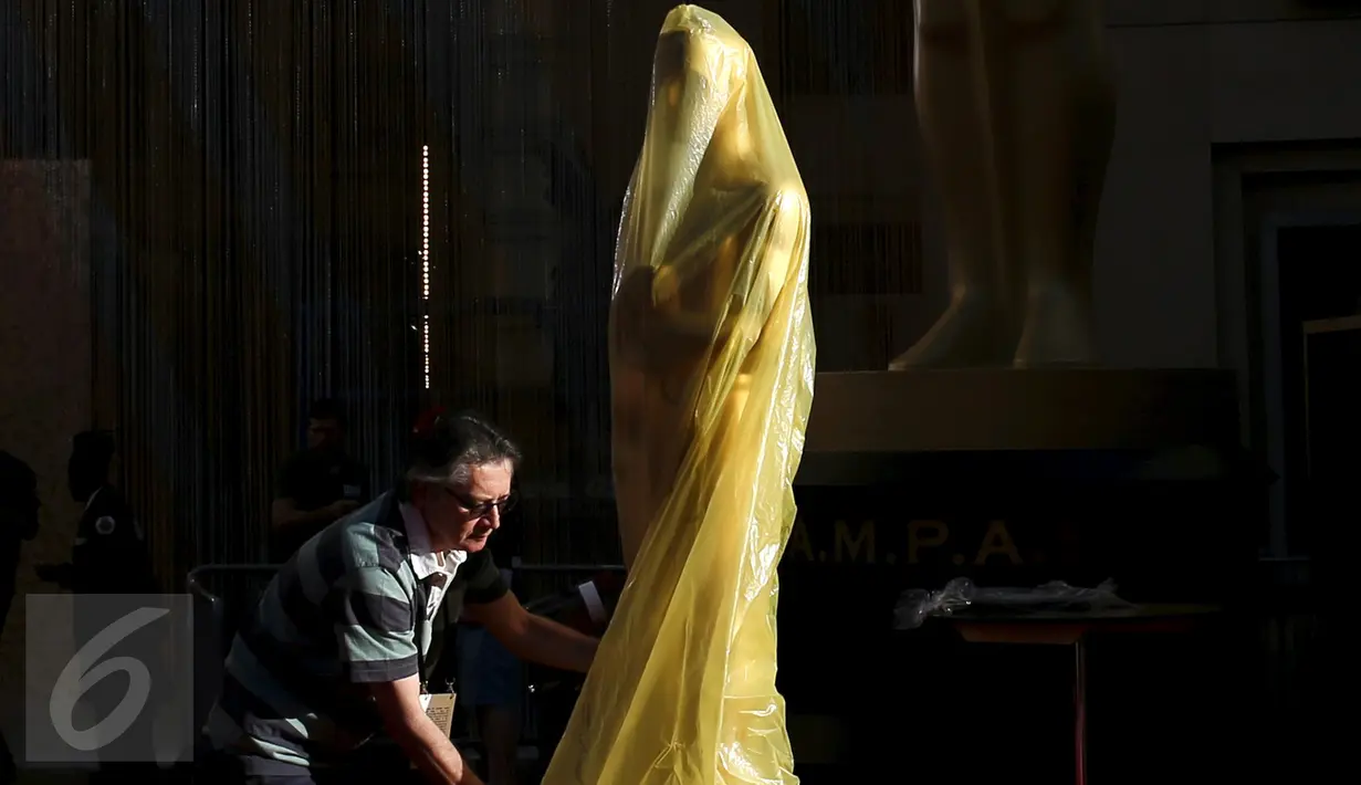 Pekerja saat akan melepas plastik yang menutupi patung Oscar dalam persiapan gelaran ke-88 Academy Awards di Hollywood, Los Angeles , California, (27/2). Penghargaan ini pertama kali diselenggarakan pada tahun 1929.  (REUTERS / Lucy Nicholson)