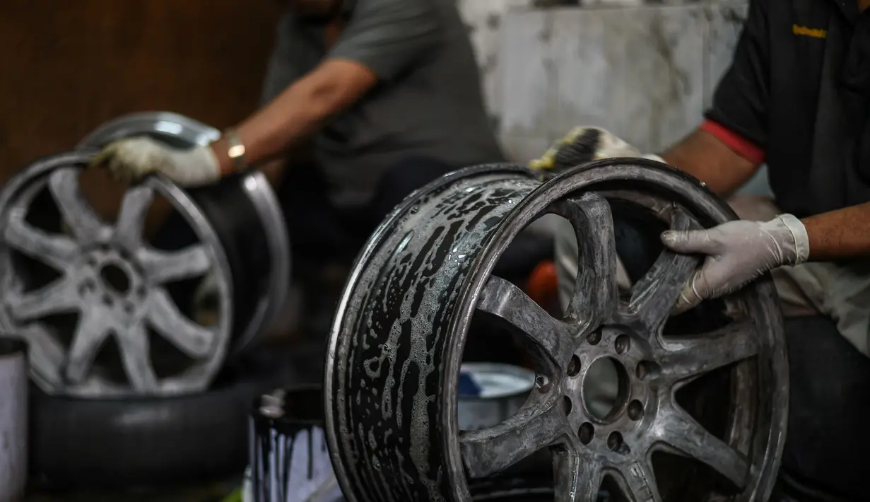 Pekerja mencuci pelek alloy sebelum dicat di sebuah bengkel di Ampang, di pinggiran kota Kuala Lumpur, Malaysia (18/7). (AFP Photo/Mohd Rasfan)