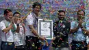 Juri Guinness, Swapnil Dangarikar memberikan sertifikat kepada gerakan GoGo Cambodia, Sann Vathana setelah syal krama sepanjang 1,149.8 meter memecahkan rekor sebagai syal tenun terpanjang dunia di Phnom Penh, Kamboja, Minggu (1/7). (AFP/TANG CHHIN Sothy)