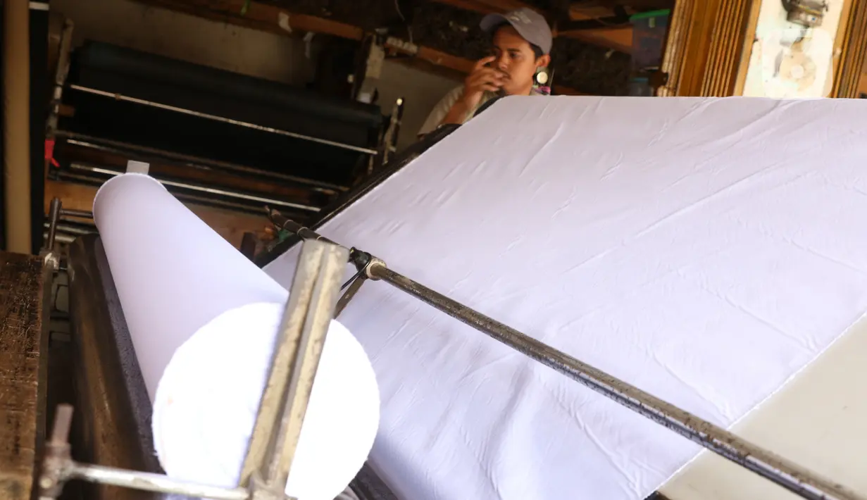 Pedagang menggulung bahan kain yang akan dijual di kawasan Tangerang, Banten, Sabtu (25/9/2021). Kementerian Perindustrian memberikan stimulus bagi industri tekstil dalam negeri berupa program Restrukturisasi Mesin/Peralatan Industri Penyempurnaan dan Percetakan Kain. (Liputan6.com/Angga Yuniar)