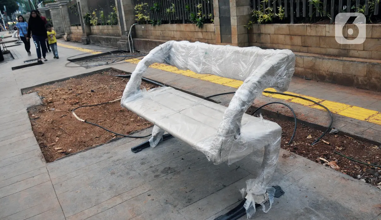 Warga melintas di trotoar di kawasan Jalan Cikini Raya, Jakarta, Minggu (8/12/2019). Sebagai bagian dari proyek revitalisasi, kini sepanjang trotoar Cikini Raya mulai terpasang bangku-bangku taman. (Liputan6.com/Helmi Fithriansyah)