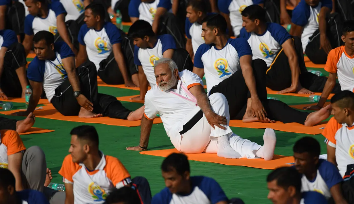 Perdana Menteri India, Narendra Modi memimpin pelaksanaan yoga massal pada Hari Yoga Internasional di Dehradun, Kamis (21/6). Modi adalah tokoh utama yang berhasil melobi PBB untuk menyatakan 21 Juni sebagai Hari Yoga Internasional. (AFP/PRAKASH SINGH)