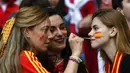 Fans wanita mengecat muka bendera Spanyol sebelum dimulainya pertandingan semifinal EURO 2020 antara Italia dan Spanyol di Stadion Wembley di London (7/7/2021). (Andy Rain/Pool via AP)