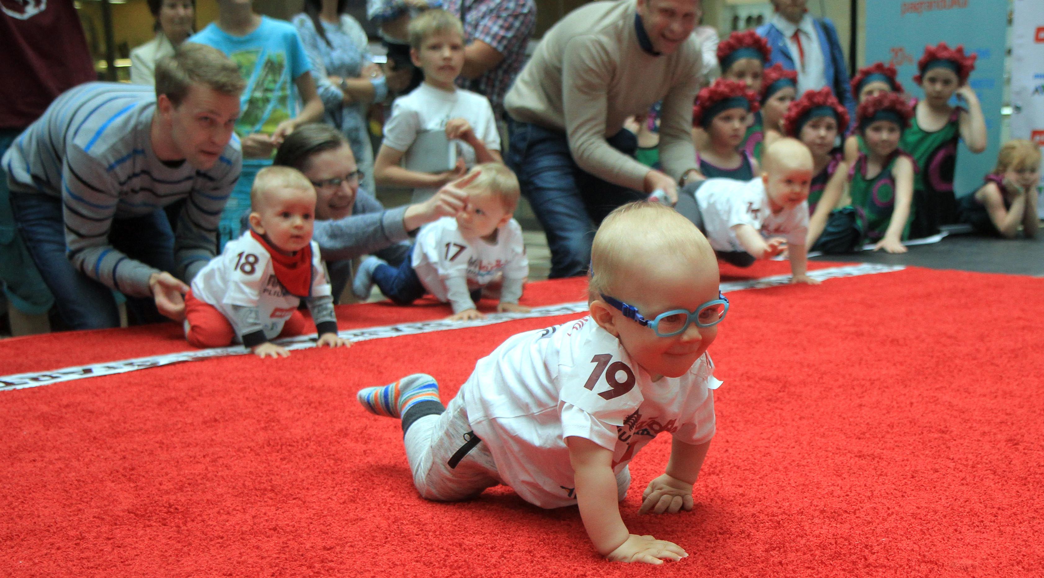 Seorang bayi mengikuti lomba merangkak untuk memperingati Hari Anak Internasional di Vilnius, Lithuania, Kamis (1/6). Orang tua memberikan iming-iming benda kesukaan buah hatinya saat mengikuti lomba. (Petras Malukas/AFP)