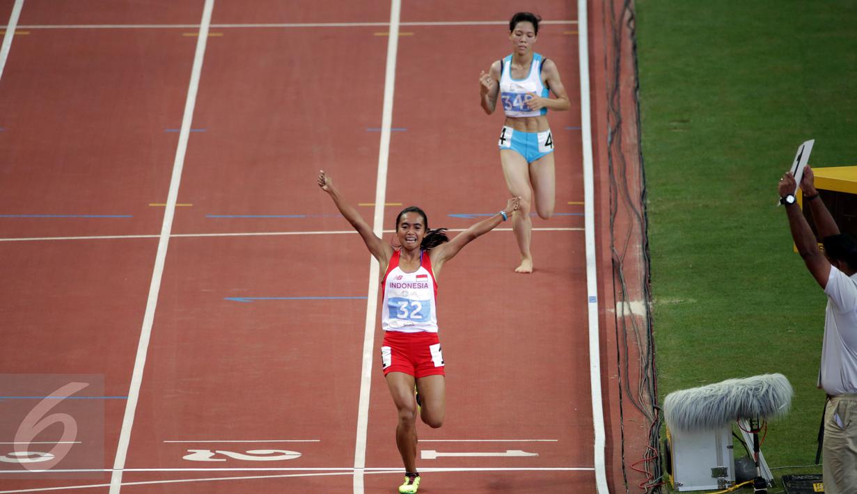 Atlet putri Indonesia, Triyaningsih mengangkat tangan usai memastikan finis pertama di nomor 10.000 M di National Stadium Singapura, Kamis (11/6/2015). Triyaningsih mencatatkan waktu 33 menit 44,53 detik. (Liputan6.com/Helmi Fithriansyah)