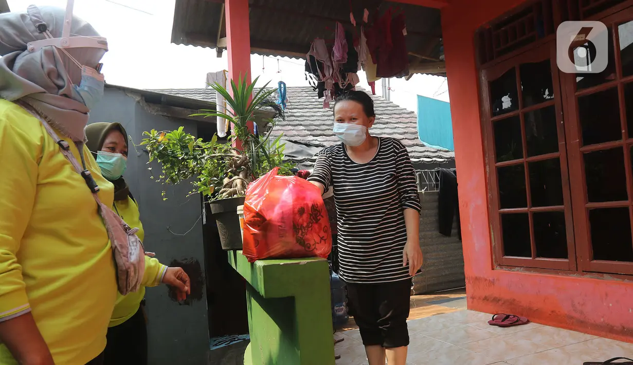 Warga menerima bantuan bahan pokok di rumahnya di RT03/RW03, Kelurahan Cilangkap, Jakarta, Jumat (21/5/2021). Sebanyak 25 paket bahan pokok dari bantuan Dinas Sosial DKI Jakarta dan swadaya warga setempat diberikan kepada 25 Kepala Keluarga. (Liputan6.com/Herman Zakharia)