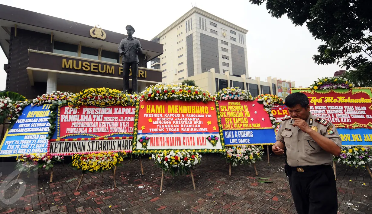 Petugas mengecek ponsel di dekat karangan bunga yang diletakkan di depan Museum Polri, Jakarta, Rabu (3/5). Ratusan karangan bunga itu terus berdatangan dan mengelilingi gedung Mabes Polri di Jalan Trunojoyo Jakarta. (Liputan6.com/Helmi Fithriansyah)