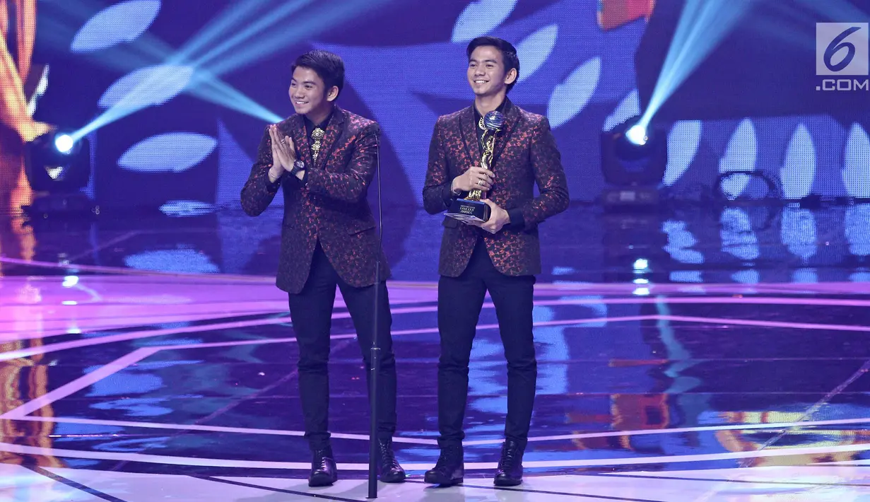 Penyanyi dangdut 2R Rizki dan Ridho D'Academy menerima piala untuk kategori duo/grup dangdut terpopuler dalam ajang Indonesian Dangdut Awards 2017 di Studio 6 EMTEK CITY, Jakarta, Jumat (13/10). (Liputan6.com/Herman Zakharia)