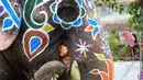 Seekor gajah makan setelah dilukis menjelang festival Hindu Rath Yatra di Ahmedabad, India (3/7/2019). Banyak kuil di India, termasuk kuil Jagannath di Ahmedabad mengadakan Rath Yatra, yang secara tradisional merupakan parade gajah yang dihias di festival-festival Hindu. (AFP Photo/Sam Panthaky)