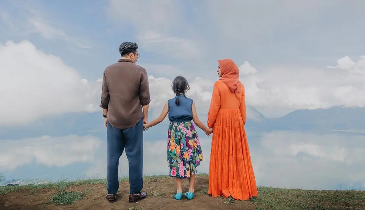 Laudya Cynthia Bella menggenggam tangan putri Engku Emran, Engku Aleesya saat foto prewedding di Sumatera Barat. Dengan bergaun oranye, Laudya Cynthia Bella tampak berfoto dengan latar belakang langit Sumetera Barat yang jernih. (instagram/iamkumbre)