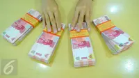 Petugas Bank menunjukkan uang pecahan rupiah di Bank BRI Syariah, Jakarta, Selasa (28/2). Pelemahan rupiah ini seiring dengan mata uang lainnya di Asia. (Liputan6.com/Angga Yuniar)