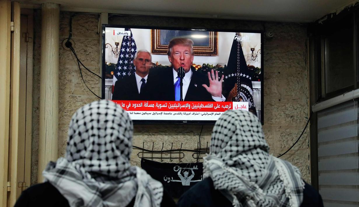 Dua pria Palestina menonton pidato Presiden AS, Donald Trump di sebuah kafe di Yerusalem (6/12). Donald Trump secara resmi mengumumkan bahwa AS mengakui Yerusalem sebagai ibu kota Israel. (AFP Photo/Ahmad Gharabli)