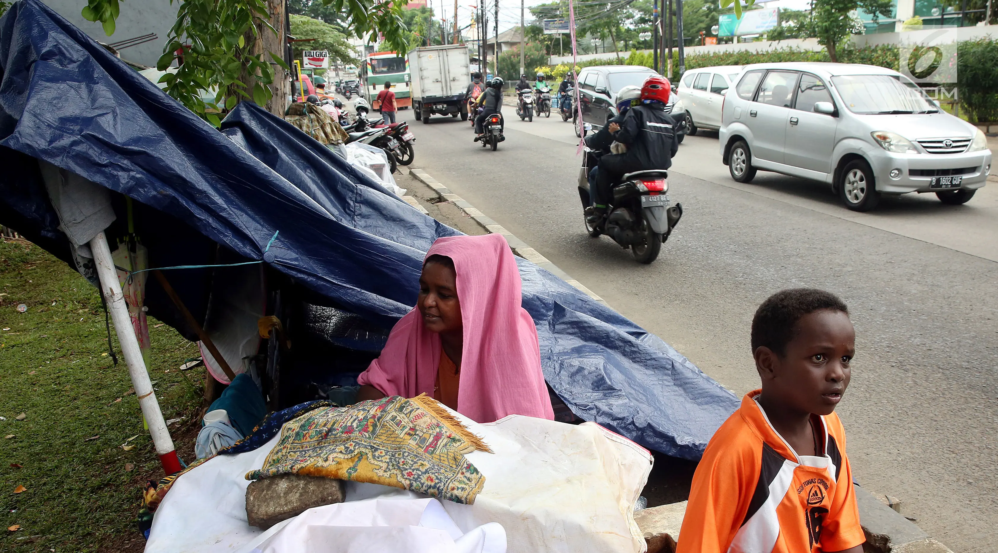 Para pencari suaka berteduh di bawah terpal di trotoar depan Rumah Detensi Imigrasi Kalideres, Jakarta, Jumat (19/1). Para pencari suaka berasal dari Afghanistan, Sudan, dan Somalia. (Liputan6.com/JohanTallo)