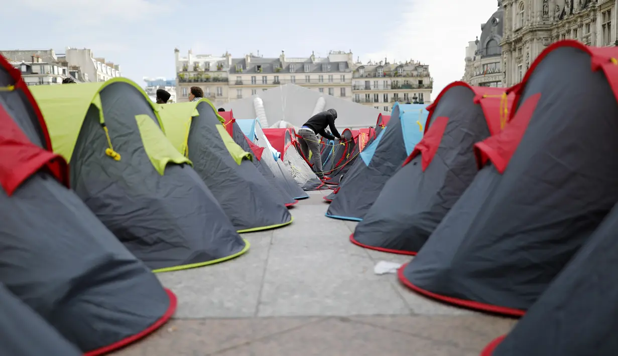 Seorang imigran menutup tendanya di kamp darurat yang didirikan di luar balai kota Paris, pada Jumat (25/6/2021). Lebih dari 300 migran mendirikan sekitar 200 tenda di luar balai kota untuk menarik perhatian terhadap kondisi mereka dan menuntut akomodasi. (AP Photo/Lewis Joly)