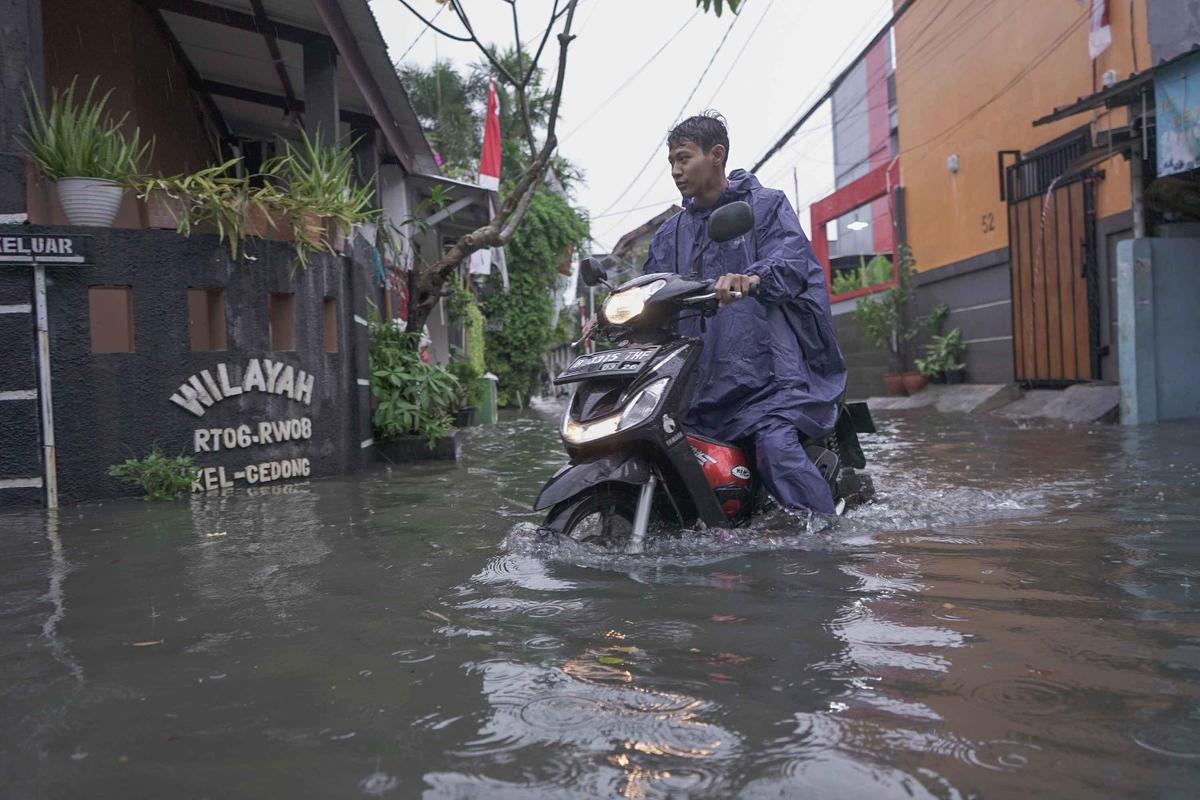 FOTO: Drainase Meluap, Warga Pasar Rebo Terobos Genangan