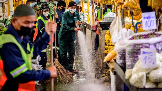 Pekerja Otoritas Metropolitan Bangkok menyapu membersihkan dan mendisinfeksi Pasar Bunga Yodpiman di Bangkok (6/1/2021).  Penghitungan terbaru mencatat adanya 729 transmisi lokal, menjadikan total kasus secara nasional menjadi 8.439. (AFP/Mladen Antonov)