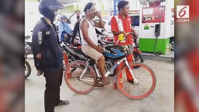 Pria ini mengisi sepeda modifikasinya gunakan bensin. Aksinya pun berbuah perhatian masyarakat sekitar.