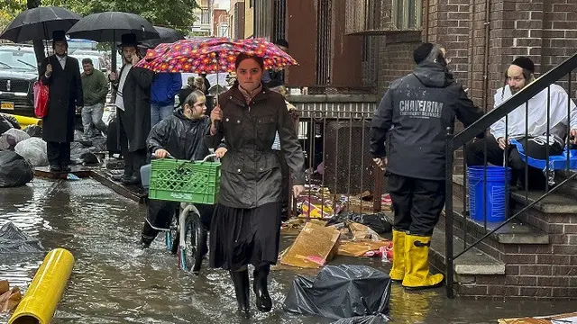 Pejalan kaki berjalan di tengah banjir di wilayah Brooklyn, New York City, Amerika Serikat, pada Jumat (29/9/2023). (Dok. AP/Jake Offenhartz)