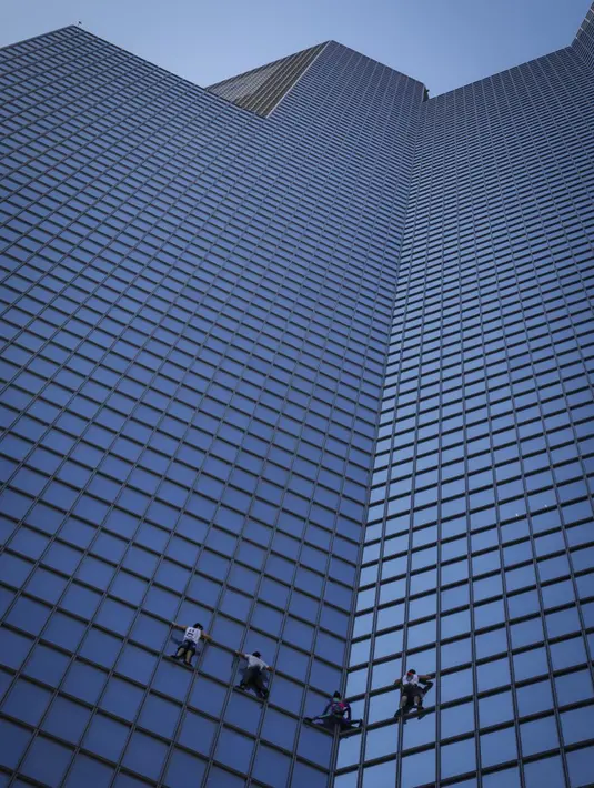 Pendaki Alain Robert (kedua kanan) atau Spiderman Prancis bersama Marcin Banot, Alexis Landot, dan Leo Urban memanjat Menara Total di La Defense, Paris, Prancis, 7 September 2021. Alain dengan tangan kosong memanjat menara setinggi 190 meter itu untuk menentang izin kesehatan. (THOMAS SAMSON/AFP)