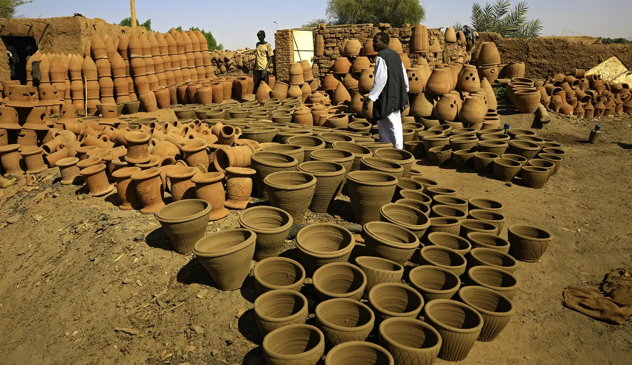 Pot tanah liat dipajang di sebuah bengkel di Omdourman, di pinggiran barat ibu kota Khartoum (19/1/2022). Para perajin tembikar di Sudan memanfaatkan tanah liat sisa banjir untuk membuat benda-benda kerajinan tersebut. (AFP/Ashraf Shazly)