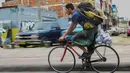 Jahn Fredy Duque bersepeda menuju tempat beraksinya di jalanan Bogota, Kolombia, Senin (24/4). Duque mencari nafkah dengan melakukan atraksi layaknya Spiderman. (AFP Photo/RAUL ARBOLEDA)