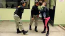 Petugas lapas dicium seorang anak yang digendong seorang narapidana di dalam penjara wanita Santa Monica, Lima, Peru (31/10). Taman kanak-kanak ini didirikan sebagai tempat pendidikan bagi anak-anak narapidana di Santa Monica. (Reuters/Mariana Bazo)