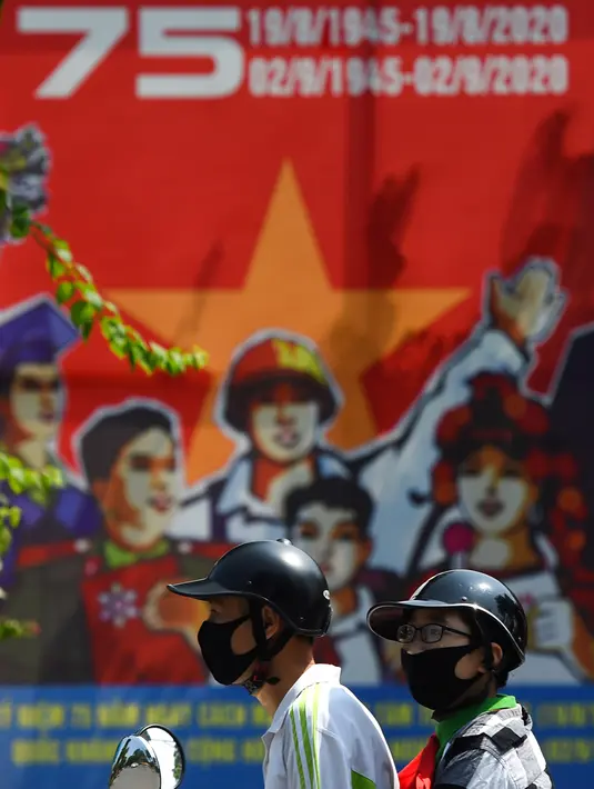 Warga mengendarai sepeda motor melewati spanduk yang menandai peringatan 75 tahun Hari Nasional Vietnam (1/9/2020). Peringatan 75 tahun Hari Nasional Vietnam jatuh pada tanggal 2 September 2020. (AFP Photo/Nhac Nguyen)