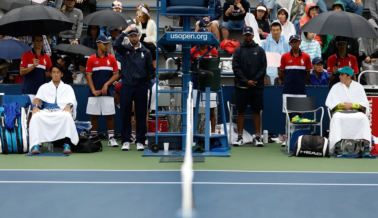Yuichi Sugita asal Jepang (kiri) dan Geoffrey Blancaneaux dari Prancis menunggu penundaan pertandingan akibat hujan selama putaran pertama turnamen tenis AS Terbuka 2017 di New York (29/8). (AP Photo / Michael Noble)
