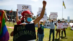 Demonstran membawa poster tuntutan saat memprotes Presiden Brasil Jair Bolsonaro dan penanganan virus corona di Brasilia, Minggu (31/1/2021). Covid-19 merenggut lebih dari 223.000 nyawa menjadikan Brasil sebagai negara dengan jumlah kematian terbanyak kedua di dunia. (Sergio LIMA/AFP)