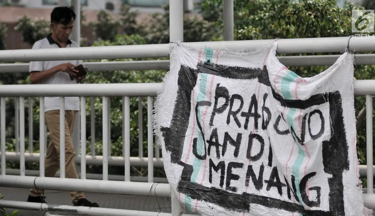 Warga melintas di dekat Spanduk Rakyat dukungan Prabowo-Sandiaga yang terpasang di JPO Jakarta, Selasa (9/4). Berbeda dengan spanduk pada umumnya, Spanduk Rakyat merupakan karung bekas yang dibuat oleh pendukung Prabowo-Sandiaga yang ditulis dengan cat atau spidol. (merdeka.com/Iqbal S. Nugroho)
