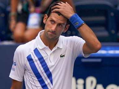 Reaksi petenis Serbia, Novak Djokovic setelah tidak sengaja memukulkan bola ke hakim garis saat kehilangan poin dari Pablo Carreno Busta (Spanyol) pada putaran keempat US Open 2020, di Flushing Meadows, Minggu (6/9/2020). Djokovic pun didiskualifikasi dari AS Terbuka 2020. (AP Photo/Seth Wenig)