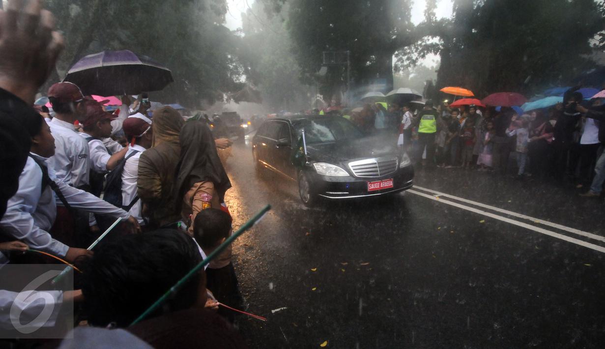 Pelajar dan warga menyambut kedatangan mobil bertuliskan Saudi Arabia di sekitar Istana Bogor, Rabu (1/3). Kedatangan Raja Salman bin Abdulaziz ke Istana Bogor disambut puluhan ribu pelajar dan warga. (Liputan6.com/Helmi Fithriansyah) 