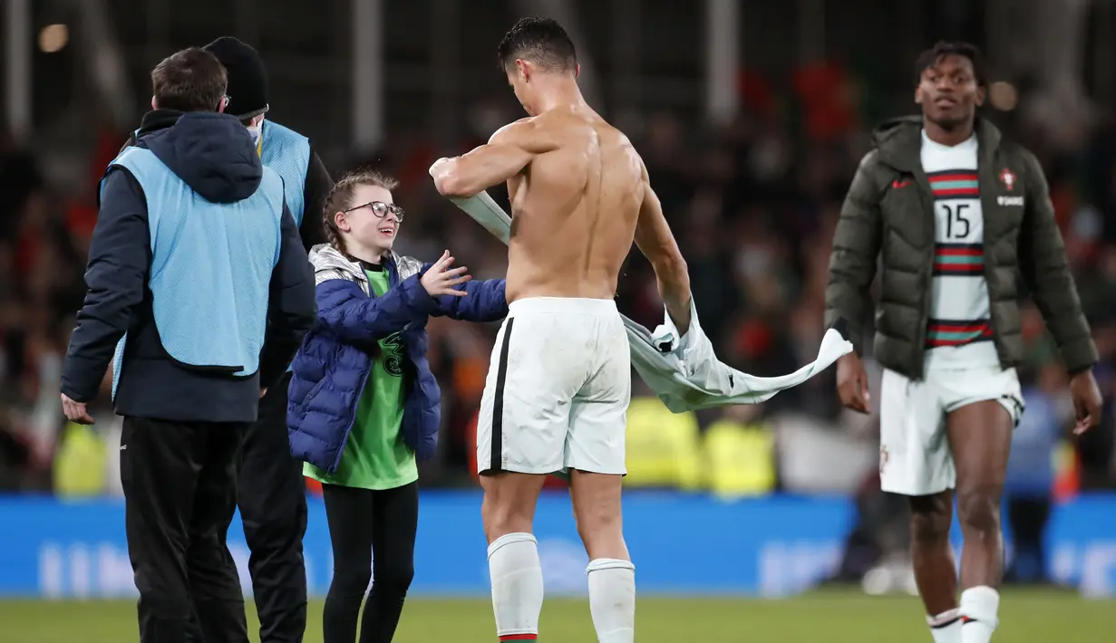 Sebuah momen manis terekam usai laga imbang antara Republik Irlandia melawan Portugal pada Kualifikasi Piala Dunia 2022. Cristiano Ronaldo terlihat memberikan pelukan dan jersey kepada fans ciliknya yang berasal dari Irlandia. (AP/Peter Morrison)