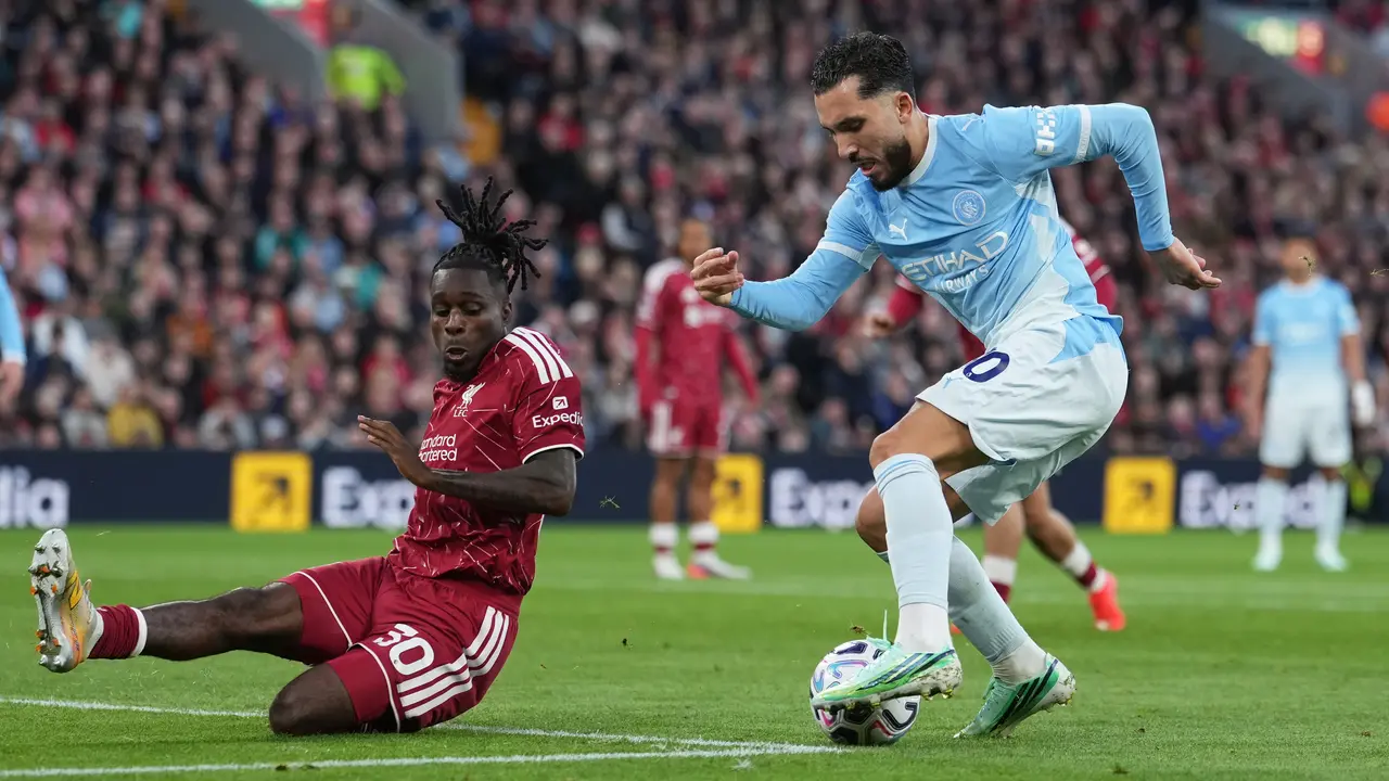 Pemain Liverpool Jeremie Frimpong (kiri) berebut bola dengan pemain Manchester City Rayan Cherki