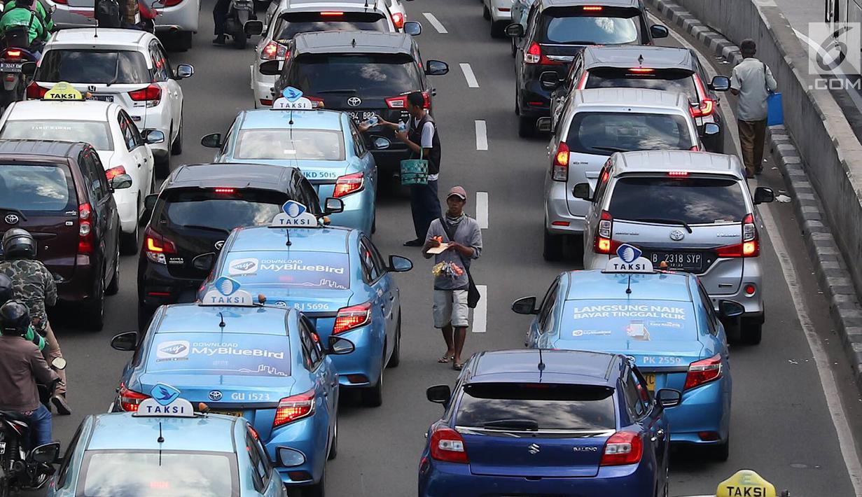 Pedagang asongan menjajakan barang dagangannya di persimpangan lampu merah di Jakarta, Jumat (22/2). Keahlian yang terbatas menyebabkan sebagian orang harus bekerja di tengah padatnya kendaraan Ibukota. (Liputan6.com/Immanuel Antonius)