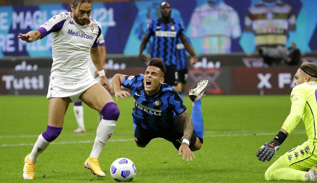 Pemain Inter Milan Lautaro Martinez (tengah) jatuh saat berebut bola dengan pemain Fiorentina Martin Caceres pada pertandingan Serie A di Stadion San Siro, Milan, Italia, Sabtu (26/9/2020). Inter Milan mengalahkan Fiorentina dengan skor 4-3. (AP Photo/Luca Bruno)
