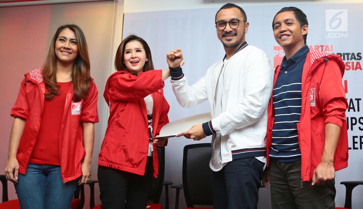 Vokalis grup band Nidji, Giring Ganesha dan Ketua Umum Partai Solidaritas Indonesia (PSI) Grace Natalie melakukan slaam komando usai menyerahkan data diri saat mendafar menjadi anggota PSI di Jakarta, Rabu (6/9). (Liputan6.com/Herman Zakharia)