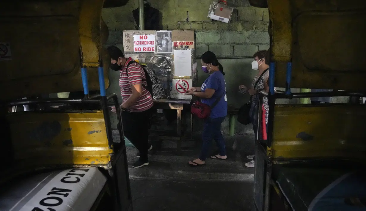 Penumpang bersiap menunjukkan kartu vaksinasi mereka sebelum menaiki jeep penumpang di sebuah terminal di kota Quezon, Senin (17/1/2022). Pemerintah Filipina melarang orang yang belum menerima vaksin COVID-19 untuk naik transportasi umum di ibu kota Manila mulai Senin ini. (AP Photo/Aaron Favila)