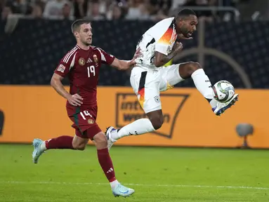 Bek Jerman Jonathan Tah menendang bola saat penyerang Hungaria Barnabas Varga mencoba menghentikannya pada ertandingan pertama grup C UEFA Nations League 2024,, Minggu (8/9/2024) dini hari WIB. (AP Photo/Michael Probst)